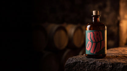 La bottiglia di Viridian su una pietra, davanti alle botti di una distilleria
